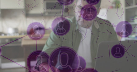 Typing man in green blazer at kitchen table, with laptop and floating nodes with user icons. Technology, connectivity, home office, innovation, digital, modern, communicationの写真素材