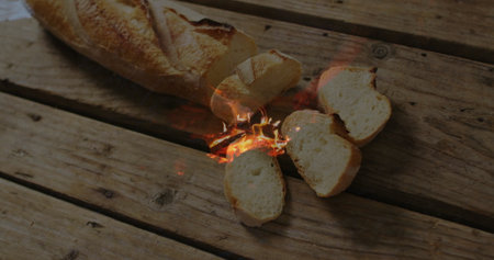 Crackling baguette loaf sitting on rustic wooden tabletop, with sliced pieces and flames. Rustic,...
