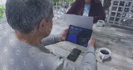 Senior couple exploring digital interface on patio deck, with tablet laptop smartphone and coffee....