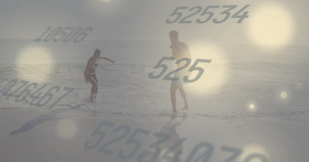 Splashing couple wearing swimwear in shallow surf at beach, with floating numeric graphics....