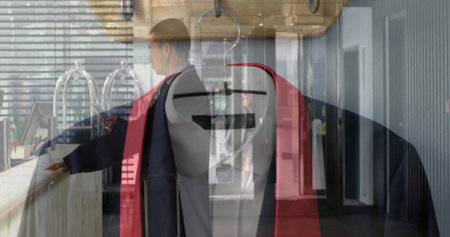 Displaying suit jacket draped with red blazer on clothes rack in hotel reception, with man pointing. Professional, boutique, modern, hospitality, style, presentation, retailの写真素材