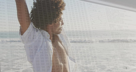Stretching man in white shirt raising arms at sandy shore left, binary code overlay, copy space. Minimalist, relaxation, wellness, outdoor, technology, vitality, tranquilityの写真素材