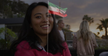 Smiling Asian woman wearing red sweater chatting on rooftop terrace, with bar counter and railing. Socializing, outdoor lounge, sunset, modern, casual, friendship, leisureの写真素材