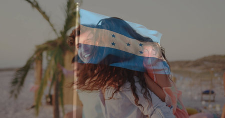 Giving piggyback ride, couple laughing on tropical beach with fruit table and superimposed flag. Romance, leisure, vacation, outdoor, playful, relaxation, scenicの写真素材