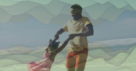 Spinning father wearing yellow tee and daughter in pink dress on sandy shoreline, with sunglasses....