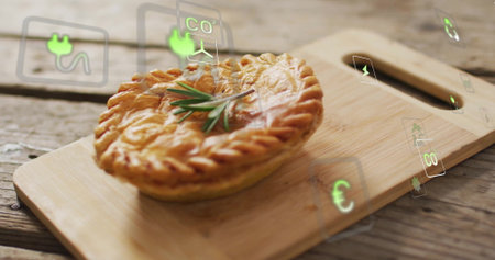 Showcasing round baked pie resting on cutting board in kitchen, with rosemary, sustainability icons. Rustic, culinary, ecofriendly, handcrafted, natural, organic, modernの写真素材