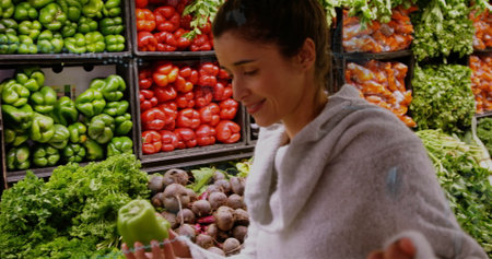 Inspecting woman examining green bell pepper in grocery store, with pepper crates, copy space. Fresh produce, healthy eating, vibrant colors, shopping, organic, natural, lifestyleの写真素材