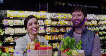 Smiling couple shopping in supermarket aisle, holding paper bags with fresh vegetables and baguette....