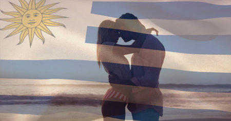Embracing couple in swimwear and shirt hugging on beach at sunset, with Uruguay flag overlay. Romance, serenity, intimacy, landscape, silhouette, tranquility, loyaltyの写真素材