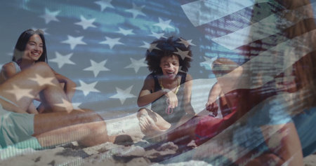 Smiling friends sitting on sandy beach, with sunglasses beach towel straw hat American flag overlay. Casual, vibrant, nostalgic, outdoor, leisure, youthful, patrioticの写真素材