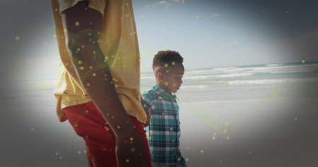 Walking father and son along sandy beach under clear sky, wearing yellow and checkered shirts. Family, coastal, leisure, outdoor, serenity, bonding, natureの写真素材