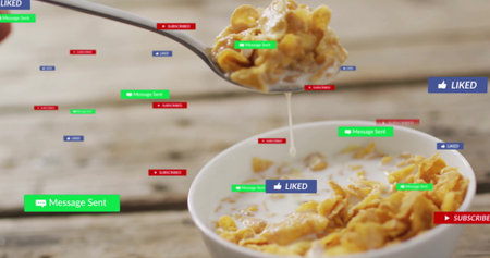 Spoon holding cornflakes, milk above bowl on wooden table with Message Sent Liked Subscribed icons....