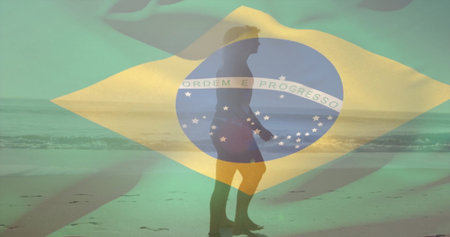 Walking surfer in board shorts carrying surfboard along beach at low tide, Brazilian flag overlay. Silhouette, beach, ocean, sunset, tranquility, adventure, outdoorの写真素材