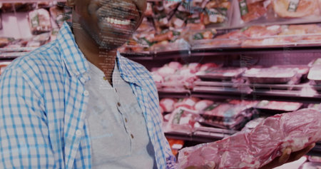 Smiling mature man holding vacuum-sealed meat inside grocery store butcher aisle, copy space. Fresh food, retail, consumer, health, cleanliness, nutrition, freshnessの写真素材