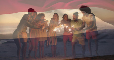 Laughing friends wearing summer clothes holding sparklers on beach at dusk, with gentle ocean waves....