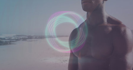 Standing shirtless male facing ocean on beach shoreline, with neon pastel circle glow, copy space....