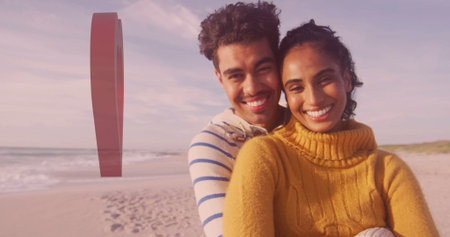 Smiling couple hugging on sandy beach at low tide, with red exclamation mark sculpture, copy space. Romantic, beach, horizon, happiness, tranquility, sculpture, sunsetの写真素材