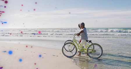 Walking mature couple pushing cruiser bicycles along ocean shoreline with gentle waves, copy space. Adventure, leisure, wellness, outdoor, tranquility, activity, friendshipの写真素材