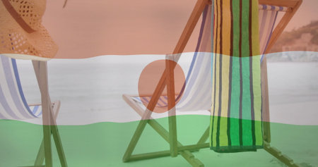 Displaying striped deck chairs positioned on sandy beach by calm sea, with straw hat and towel. Coastal, leisure, relaxation, rustic, outdoor, vacation, scenicの写真素材