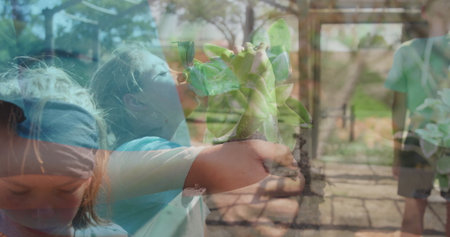 Sniffing girl in short-sleeve blue shirt lifting succulent pot at nursery aisle with metal frames. Botanical, childhood, exploration, nature, greenery, curiosity, vibrantの写真素材