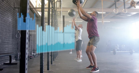 Throwing medicine ball man wearing sportswear doing wall ball in CrossFit gym, copy space. Dynamic,...