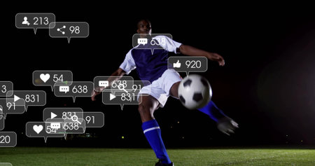 Kicking soccer player wearing purple jersey on pitch at night, with ball and floating social icons. Athletic, vibrant, competitive, dynamic, digital, energetic, nighttimeの写真素材