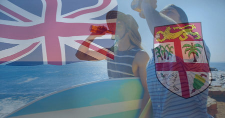 Surfers wearing straw hat, beanie holding surfboard, beer bottles on rocky beach, with flag overlay. Beach, coastal, leisure, casual, outdoor, adventure, friendshipの写真素材