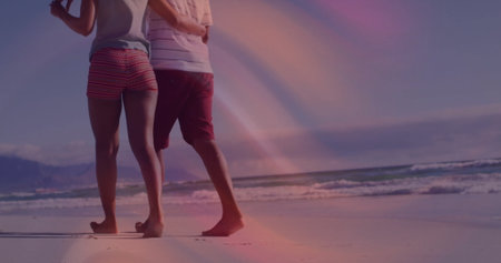 Walking couple in casual beachwear barefoot along wet sand on beach, with ocean waves and coastline. Romance, adventure, serenity, vacation, outdoor, leisure, minimalismの写真素材