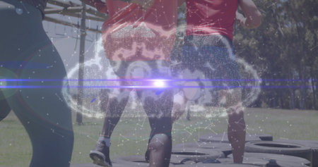 Four adults in athletic wear navigating rubber tire course in park, with digital cloud overlay. Outdoor, fitness, teamwork, endurance, innovation, vitality, challengeの写真素材