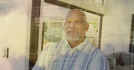 Standing man wearing striped shirt scanning data panels near sliding glass door at living room. Technology, interior, modern, analysis, interface, data, innovationの写真素材