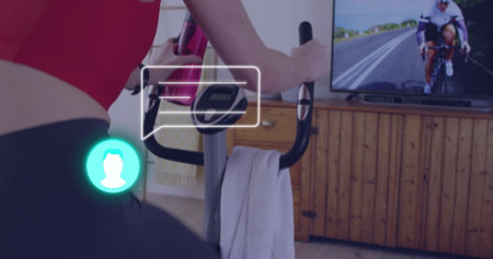 Pedaling woman on stationary bike at home, holding water bottle, towel, TV on sideboard, copy space....
