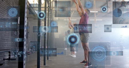 Extending arms overhead man wearing maroon shirt at training gym, with digital HUD overlay. Fitness, strength, teamwork, modern, athletic, innovation, motivationの写真素材