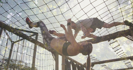 Climbing fit friends navigating cargo net on obstacle course, with wooden beams, metal ladder rungs....