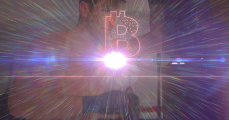 Standing adult male projecting Bitcoin symbol in minimalist interior, with colorful lens flares. Futuristic, tech, digital, innovation, cyber, neon, scienceの写真素材