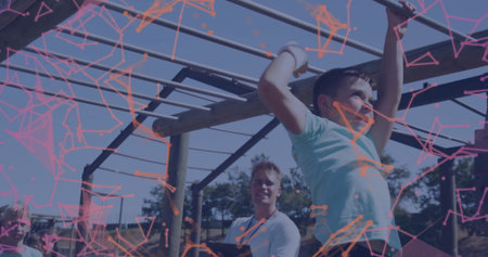 Swinging boy in teal t-shirt crossing monkey bars at grassy obstacle course, wristbands, copy space....