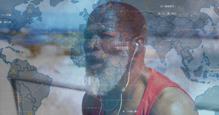 Man in red tank top and earphones examining digital interface at gym, with world map. Technology, fitness, data, connectivity, innovation, digital, healthの写真素材