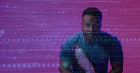 Holding tennis racket, man wearing teal sports T shirt posing in magenta-purple studio, copy space. Athlete, sportswear, digital backdrop, futuristic, energy, determination, vibrantの写真素材