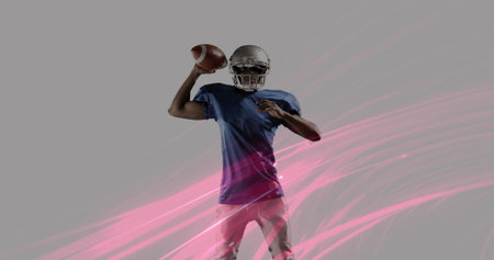 Holding football, preparing to pass in studio, quarterback wearing helmet with pink streak graphics....