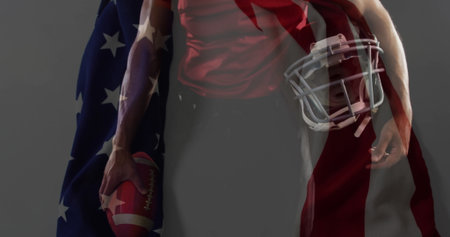 Posing athlete wearing red jersey holding football and helmet in studio, with faded US flag overlay. Athlete, sportswear, dynamic, patriotism, strength, determination, studioの写真素材