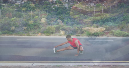 Male athlete wearing red top and black shorts performing side lunge on paved road, with wristwatch....