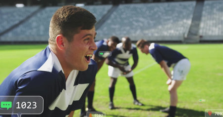 Catching breath Hispanic rugby player bending forward on stadium field, with uniform, chat icons. Athletes, teamwork, sportsmanship, digital communication, stadium, performance, motivationの写真素材