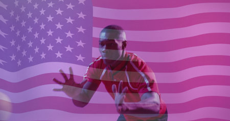 Crouching athlete wearing red jersey reaching for volleyball in studio, with American flag backdrop. Athlete, sports, competition, patriotism, determination, dynamic, energeticの写真素材