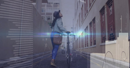Walking Asian woman pushing bicycle along urban alley, carrying brown satchel and wearing black hat....