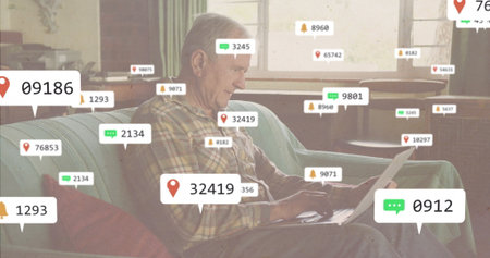 Typing senior man on laptop on sofa in living room, with floating notification icons. Retirement,...