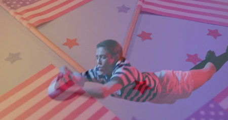 Diving performer wearing striped outfit reaching in studio, with American flag panels and sphere....