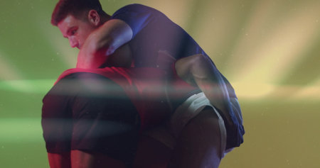 Lifting male athlete carrying partner in performance studio, with colored lights and sportswear. Movement, strength, competition, theatrical, dynamic, fitness, energeticの写真素材