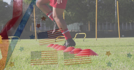 Stepping athlete wearing red shorts on field, with red cones, yellow hurdles and poles, copy space. Athlete, agility, training, sport, performance, outdoors, competitionの写真素材