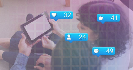 Interacting two friends tapping blank-screen tablet in living room, with social media icons....