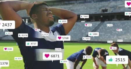 Gripping head soccer player in navy jersey on pitch at stadium, with floating social media icons. Athletes, teamwork, stadium, landscape, endurance, competition, motivationの写真素材