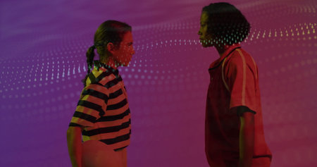 Posing two women wearing sportswear facing each other in studio with ball and light projection. Athletes, teamwork, vibrant, modern, fitness, collaboration, dynamicの写真素材